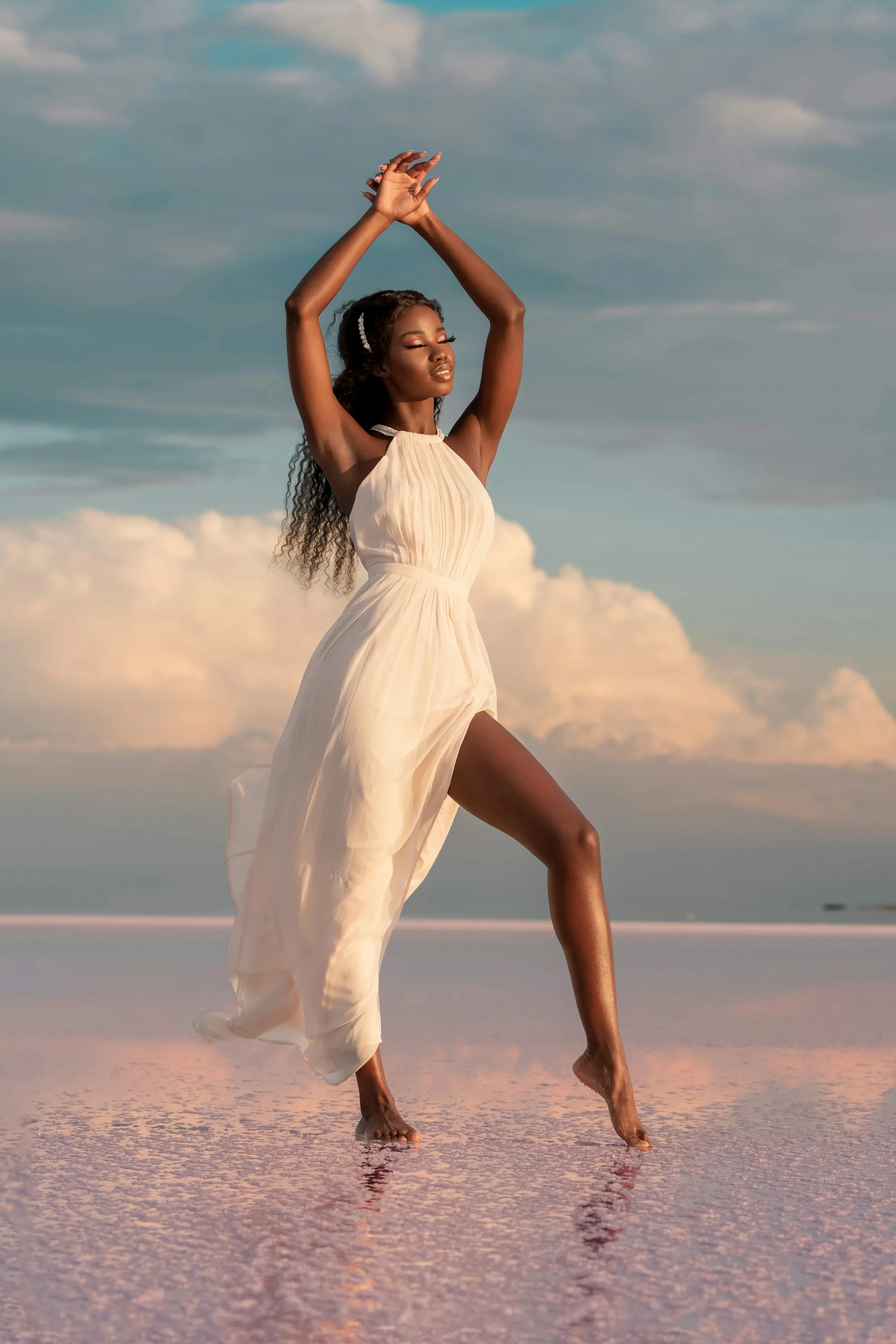 A model in an ivory gown poses at the end of a lit runway