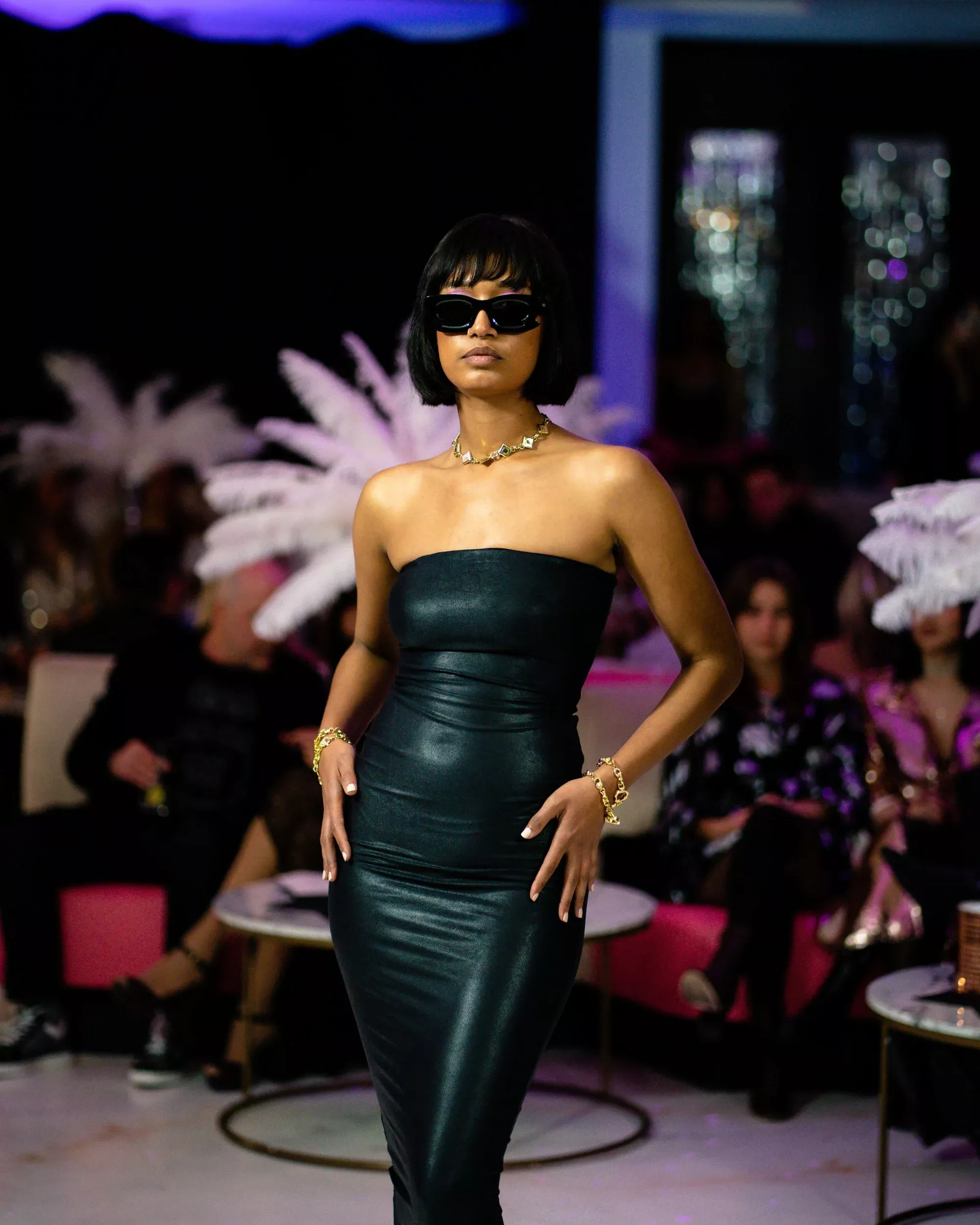 A model in an embroidered gown walks toward a lit stage
