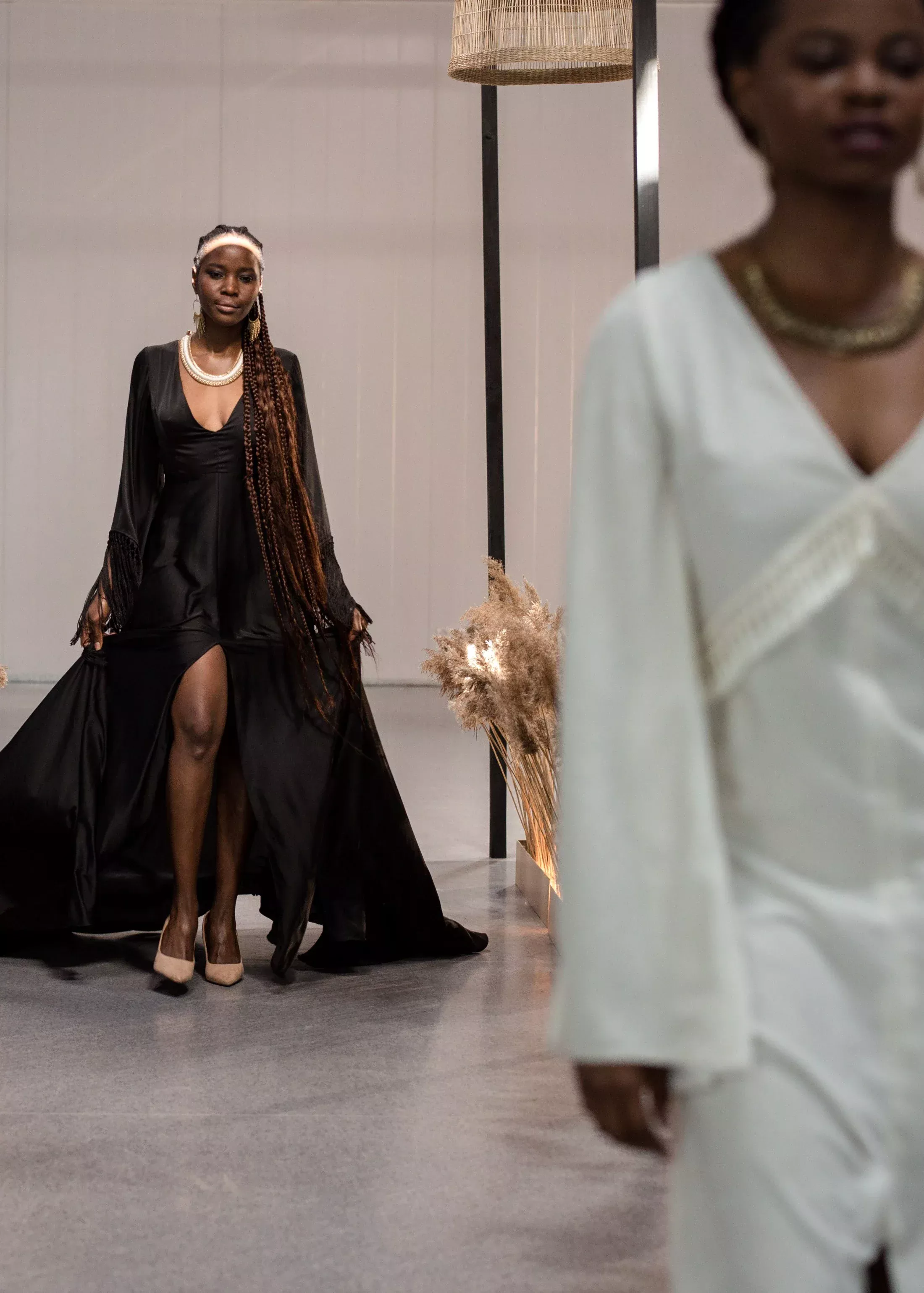 A model in a black strapless couture gown poses on a marble staircase during New York Fashion Week